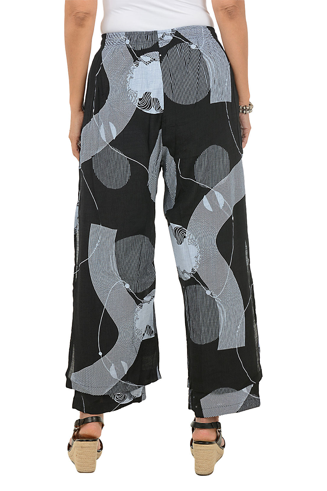 Black pants with gray circle pattern worn by a person on a white background. Back shot.