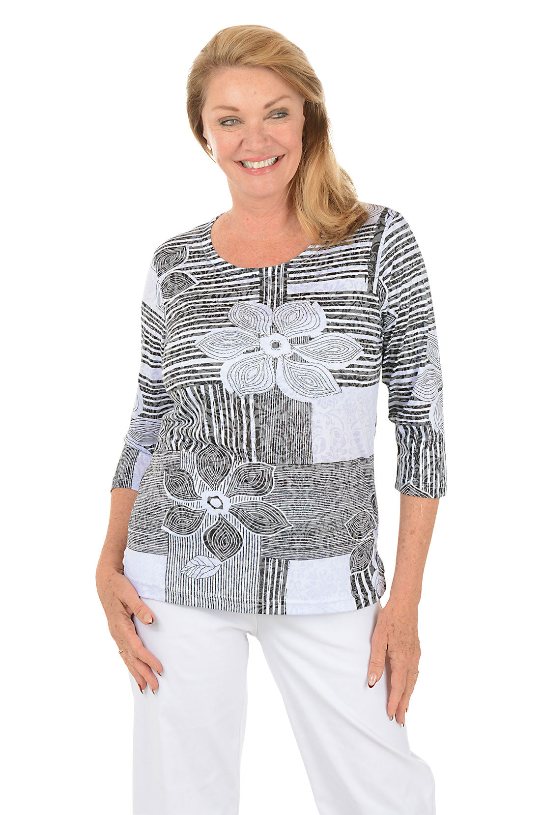 Woman wearing a black and white patterned top with floral designs on a white background. Second front shot.