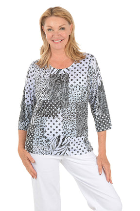 Woman wearing a patterned top and white pants on a white background.