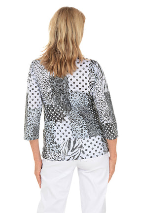 Woman wearing a patterned top and white pants on a white background. Back shot.