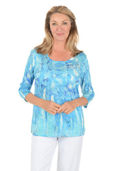 Woman wearing a blue patterned top on a white background.