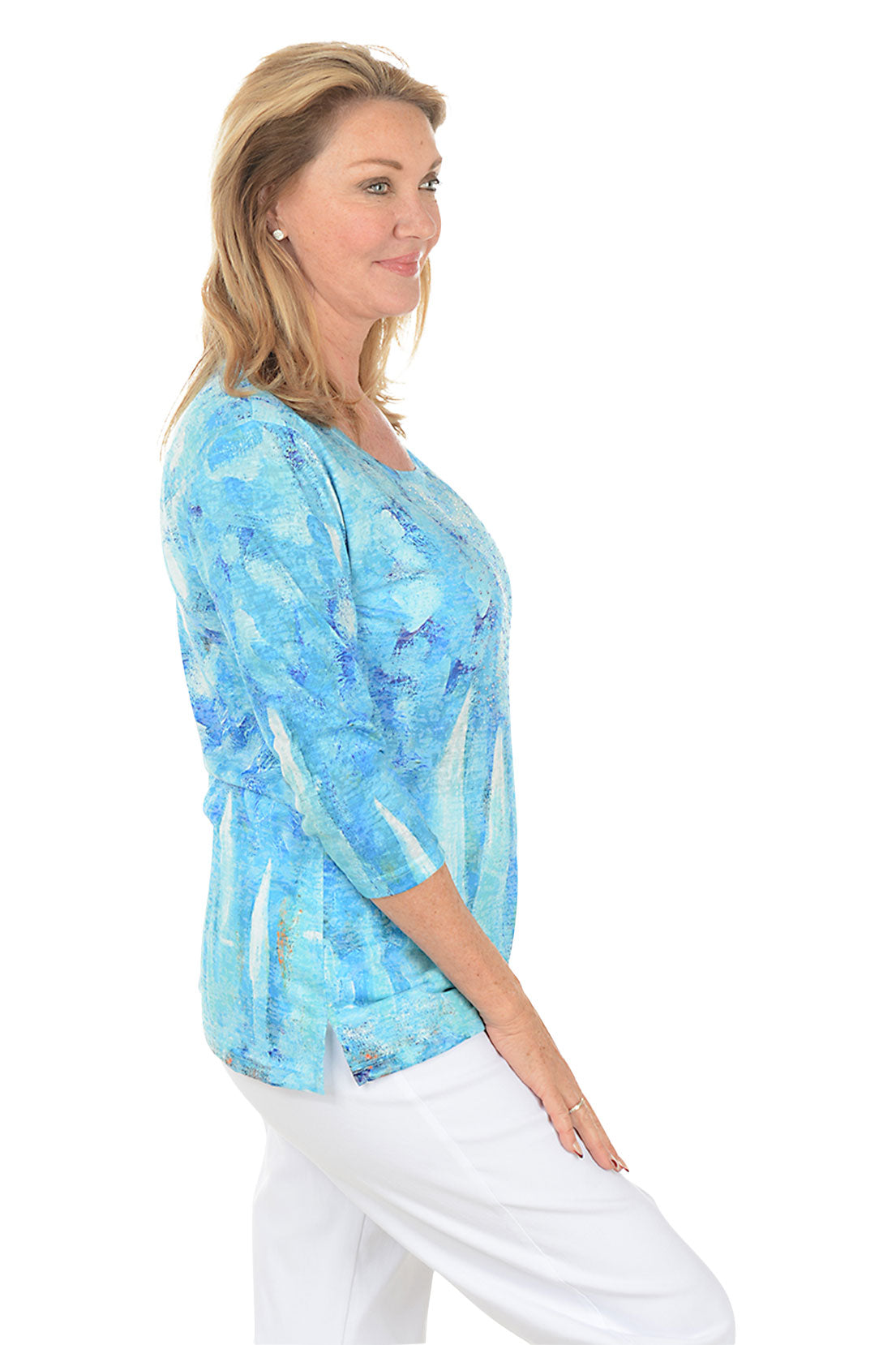 Woman wearing a blue patterned top on a white background. Side shot.