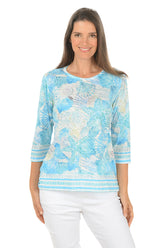 Woman wearing a blue patterned top on a white background.