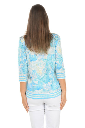 Woman wearing a blue patterned top on a white background. Back shot.
