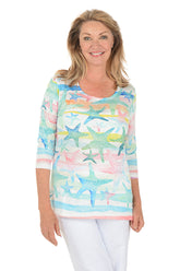 Woman wearing a colorful starfish-patterned top on a white background.