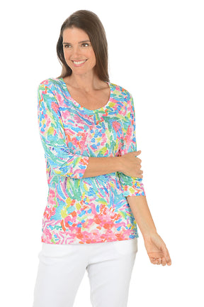 Woman wearing a colorful patterned top on a white background.