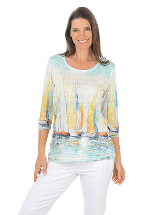 Woman wearing a colorful sailboat print top on a white background.