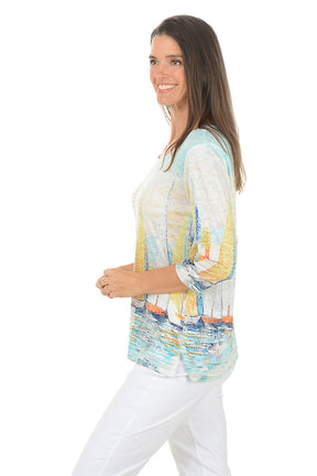 Woman wearing a colorful sailboat print top on a white background. Side shot.