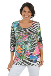 Woman wearing a colorful zebra print top with floral patterns on a white background.