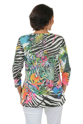 Woman wearing a colorful zebra print top with floral patterns on a white background. Back shot.