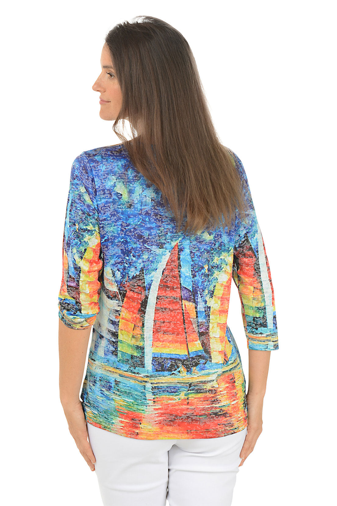 Woman wearing a colorful sailboat print top on a white background. Back shot.