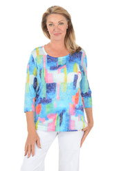 Woman wearing a colorful abstract patterned top on a white background.