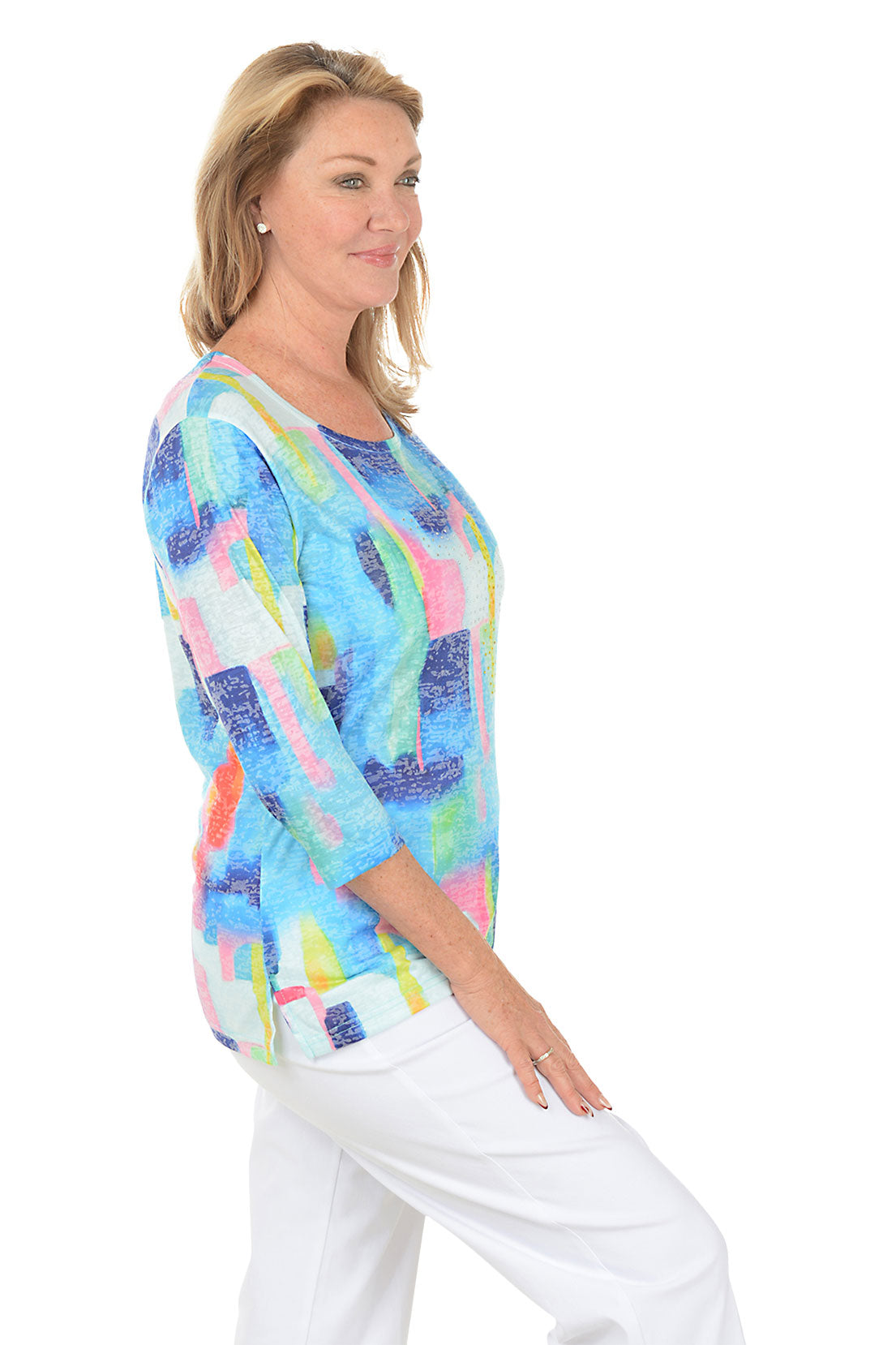 Woman wearing a colorful abstract patterned top on a white background. Side shot.