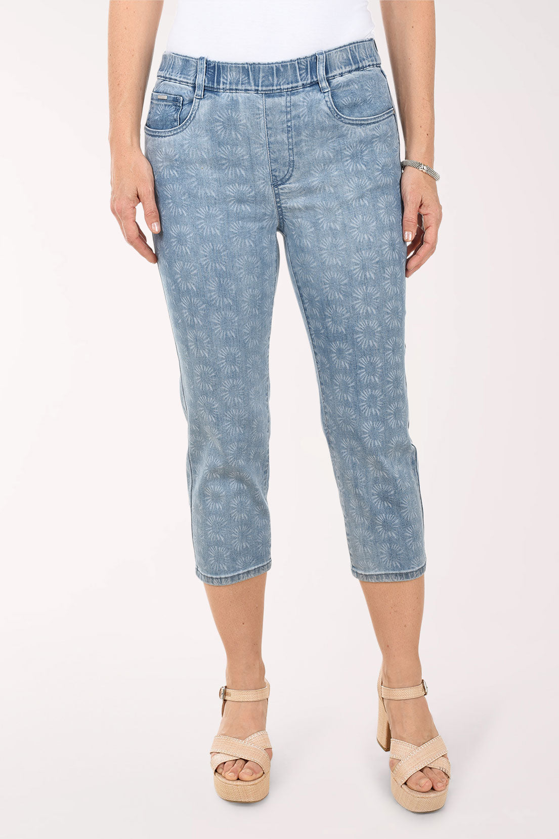 Person wearing light blue denim capri pants on a white background