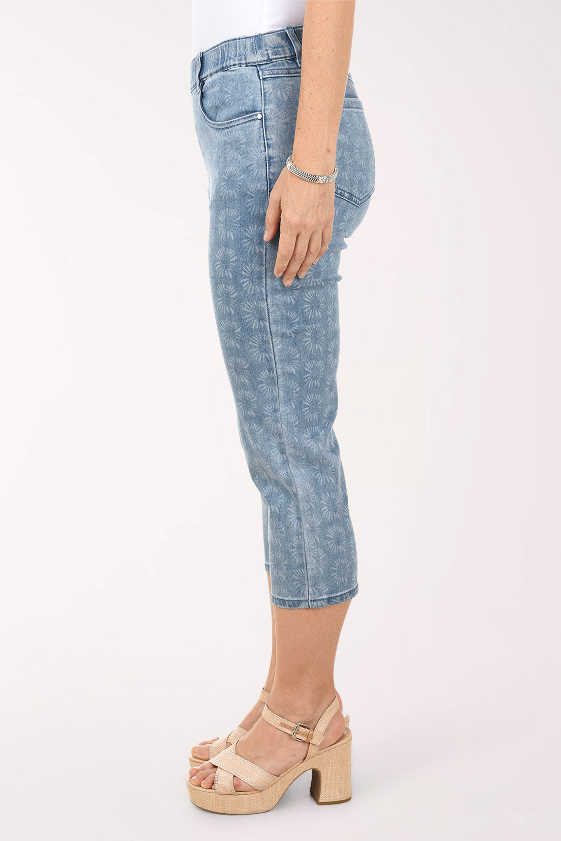Person wearing light blue denim capri pants on a white background