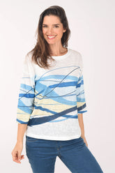Woman wearing a white sweater with blue and yellow abstract patterns on a white background