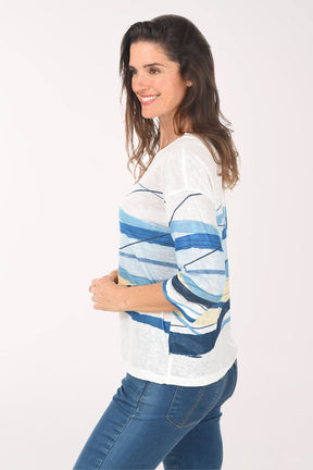 Woman wearing a white sweater with blue and yellow abstract patterns on a white background
