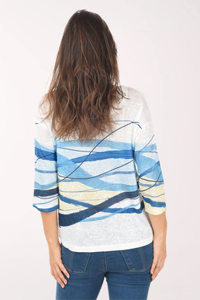 Woman wearing a white sweater with blue and yellow abstract patterns on a white background