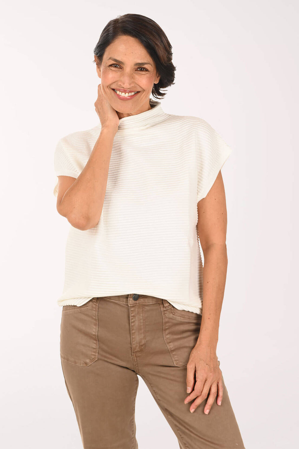 A woman modeling a white ribbed short-sleeve mock neck top paired with brown pants, photographed against a clean white studio background.