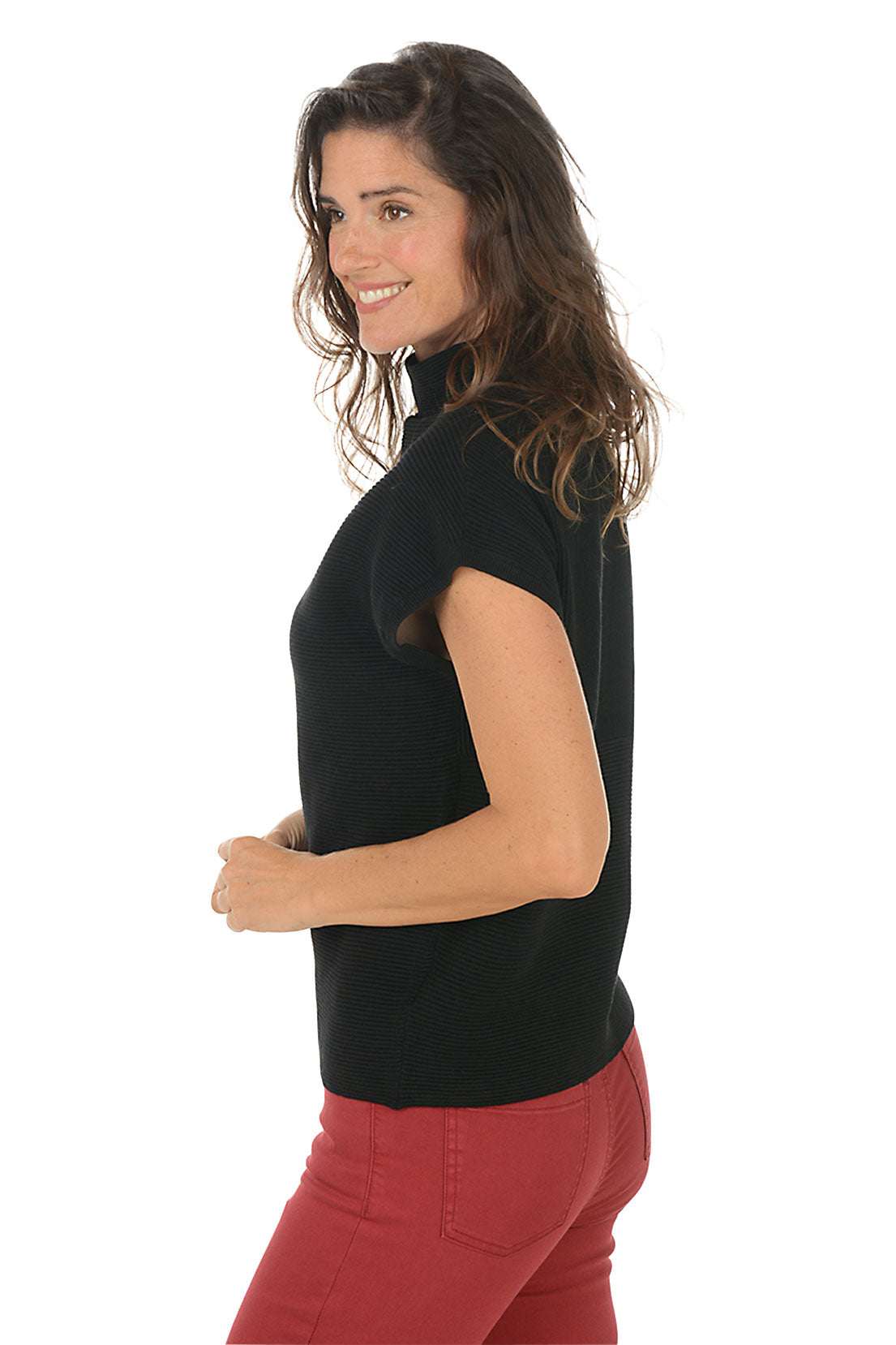 Woman wearing a black sleeveless top and red pants on a white background. Side shot.