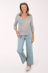 Woman wearing a striped sweater and light blue jeans on a white background