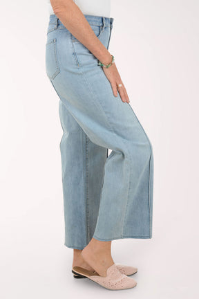 Woman wearing a striped sweater and light blue jeans on a white background