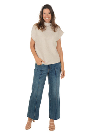 Person wearing blue cropped jeans paired with a short sleeve brown sweater on a white background. Full length shot.
