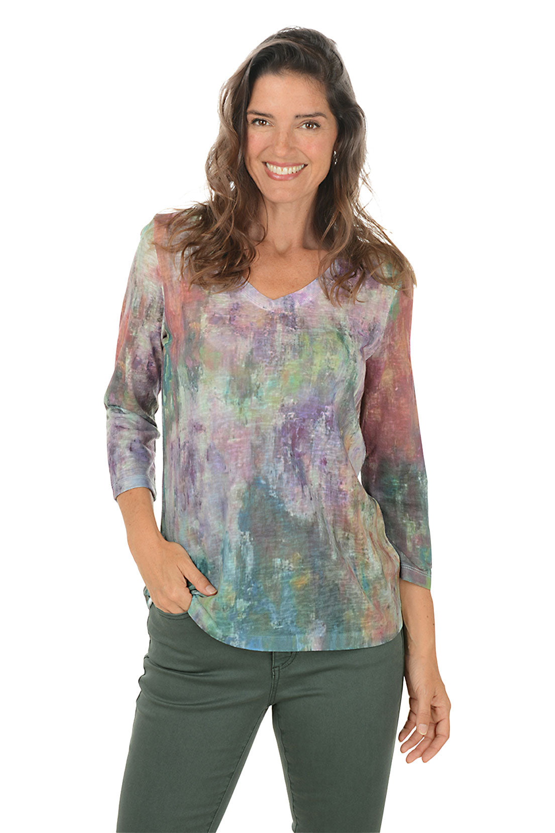Woman wearing a v-neck 3/4 sleeve colorful tie-dye shirt and green pants on a white background.