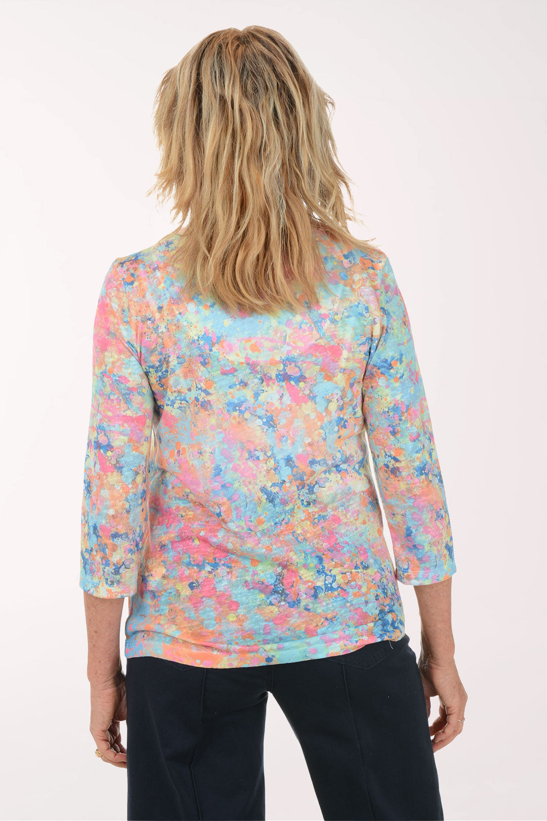 A woman wearing a multicolored v-neck 3/4 sleeve top.