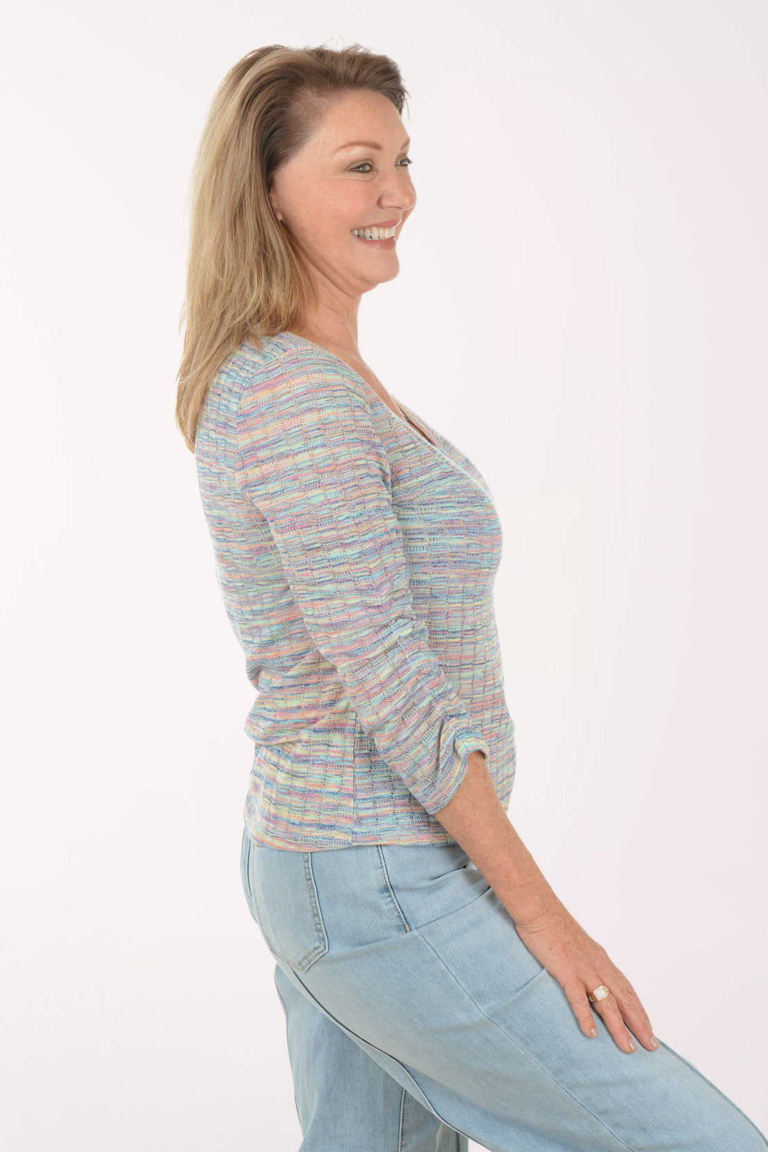 Woman wearing a multicolored striped sweater and light blue jeans on a white background