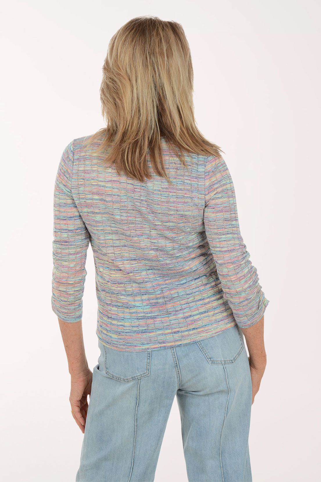 Woman wearing a multicolored striped sweater and light blue jeans on a white background