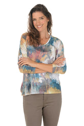 Woman wearing a scoop neck 3/4 sleeve colorful tie-dye shirt with arms crossed on a white background.