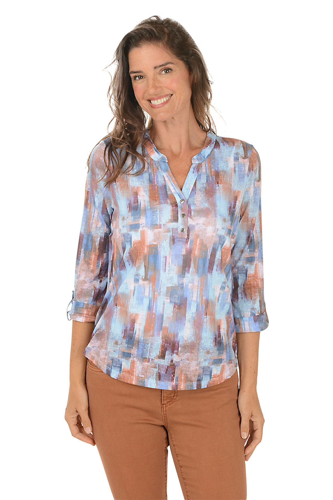 Woman wearing a patterned blouse with brown pants on a white background.