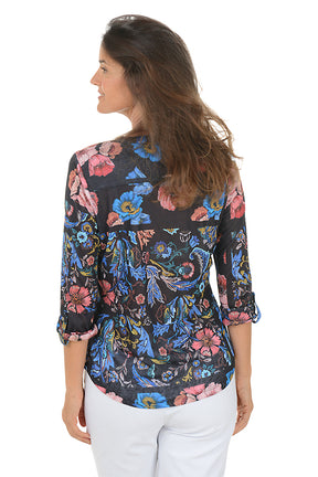 Woman wearing a 3/4 sleeve floral blouse with a v-neck neckline with a white background. Back shot.