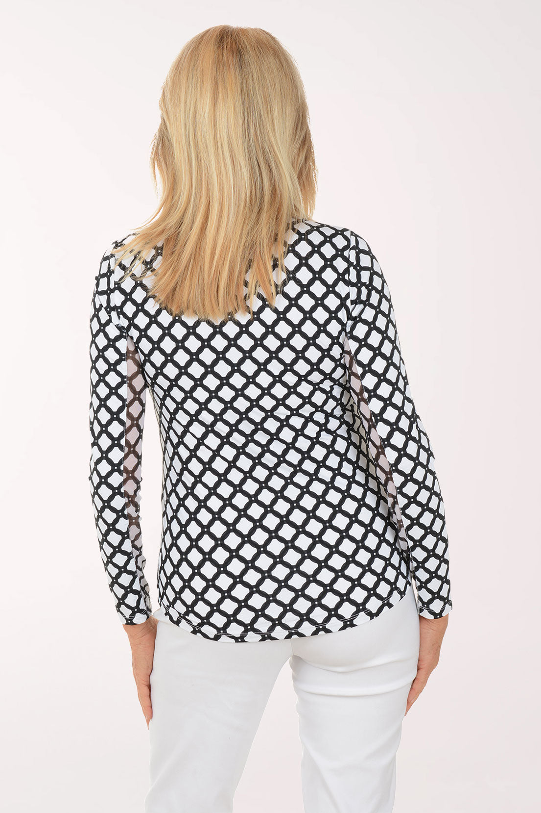 Woman wearing a black and white checkered blouse with white pants on a white background