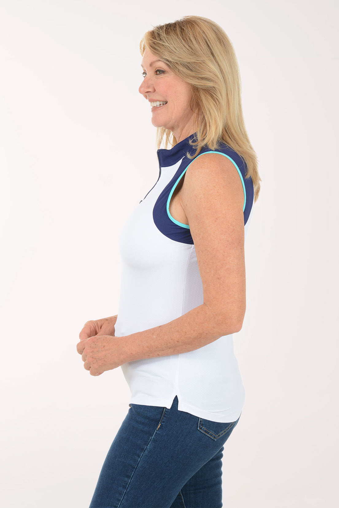 Woman wearing a sleeveless white top with navy accents on a white background