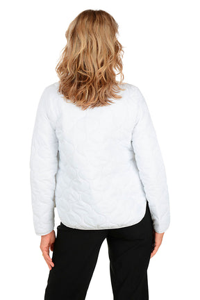 A woman wearing a white quilted puffer jacket. Back shot.