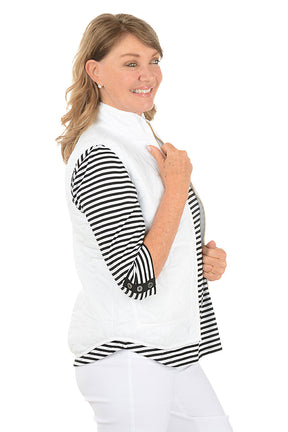 Woman wearing a white quilted puffer vest. Side shot.