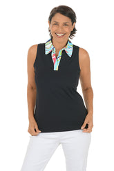 Woman wearing a black sleeveless top with a colorful collar and white pants on a white background.