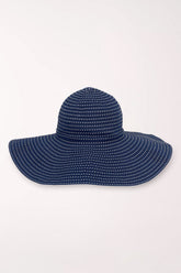 Navy blue sun hat with white polka dots on a light gray background