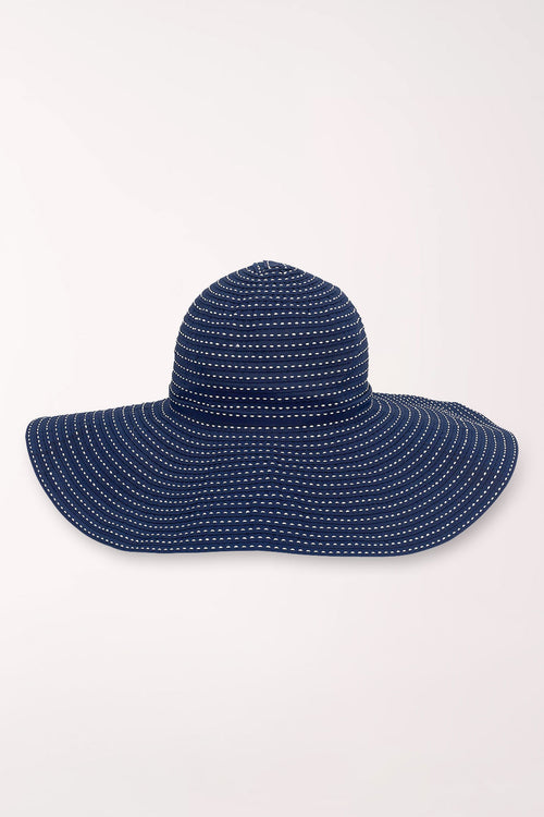 Navy blue sun hat with white polka dots on a light gray background