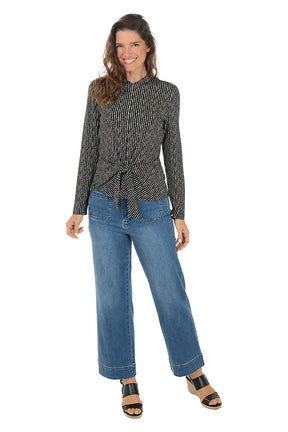 Woman wearing a patterned shirt and blue jeans on a white background. Second front shot.