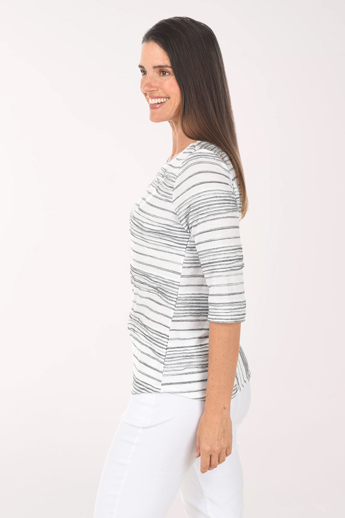 Woman wearing a striped sweater and white pants on a white background
