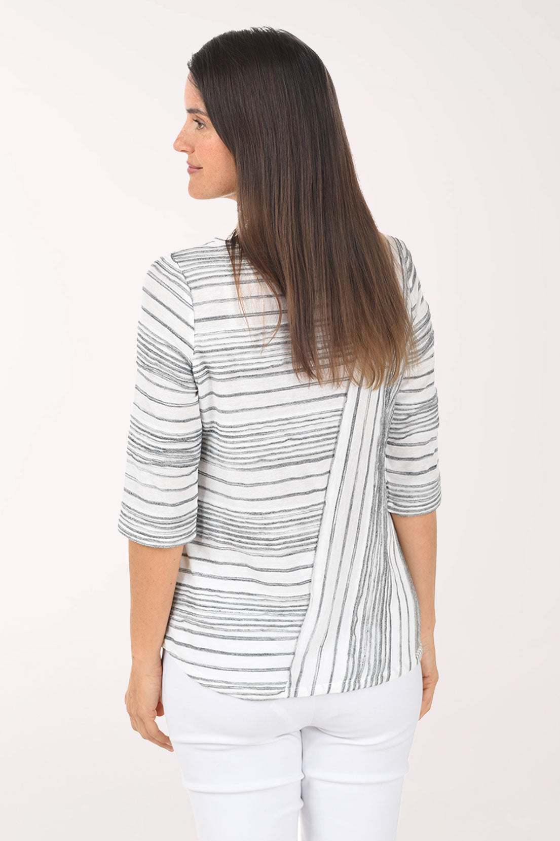 Woman wearing a striped sweater and white pants on a white background