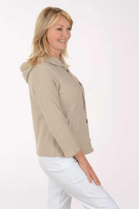 Woman wearing a beige jacket with black buttons on a white background