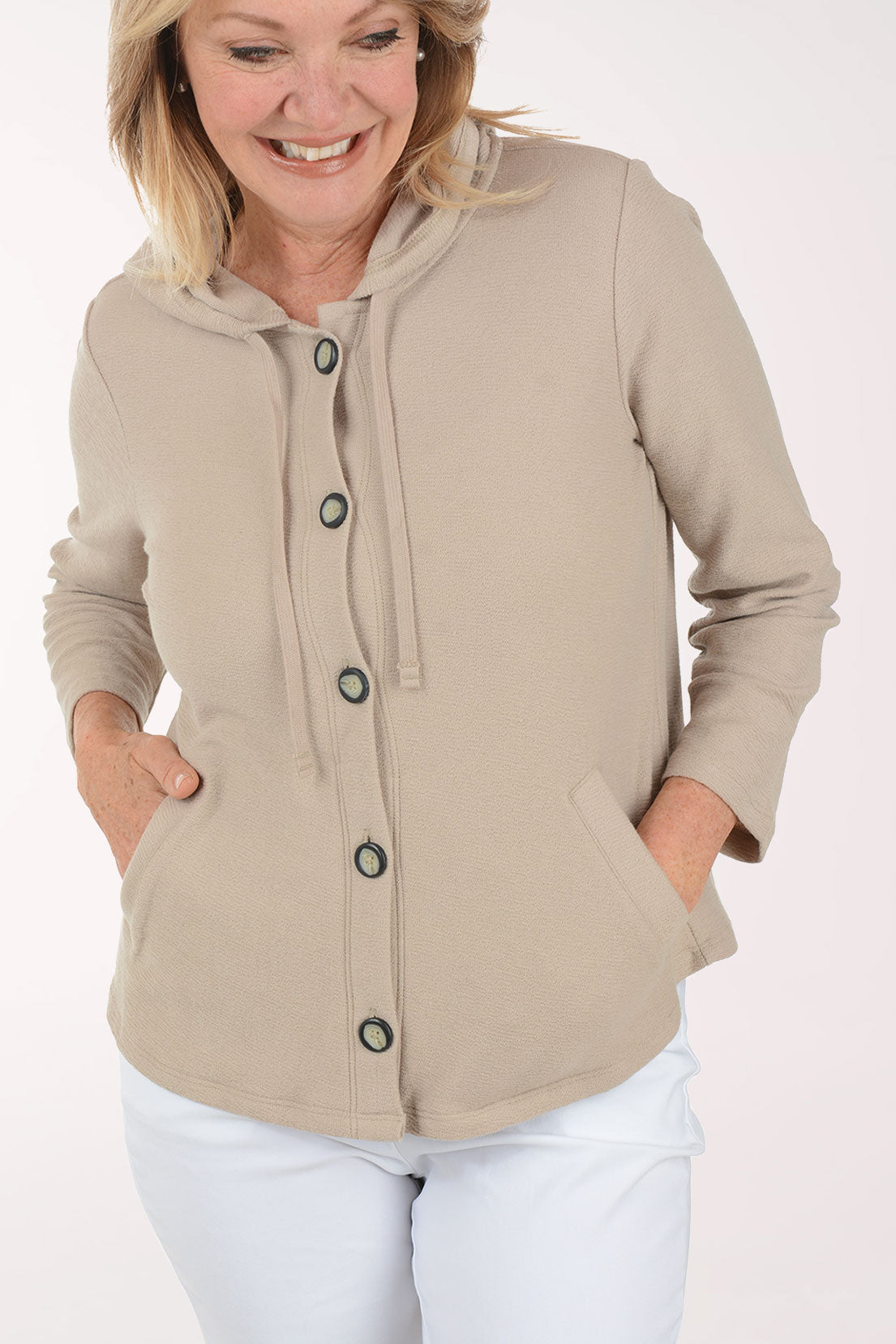 Woman wearing a beige jacket with black buttons on a white background