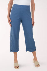 Blue pants with button details worn by a person on a white background