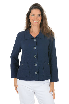 Woman wearing a navy blue collared jacket with button details on a white background.