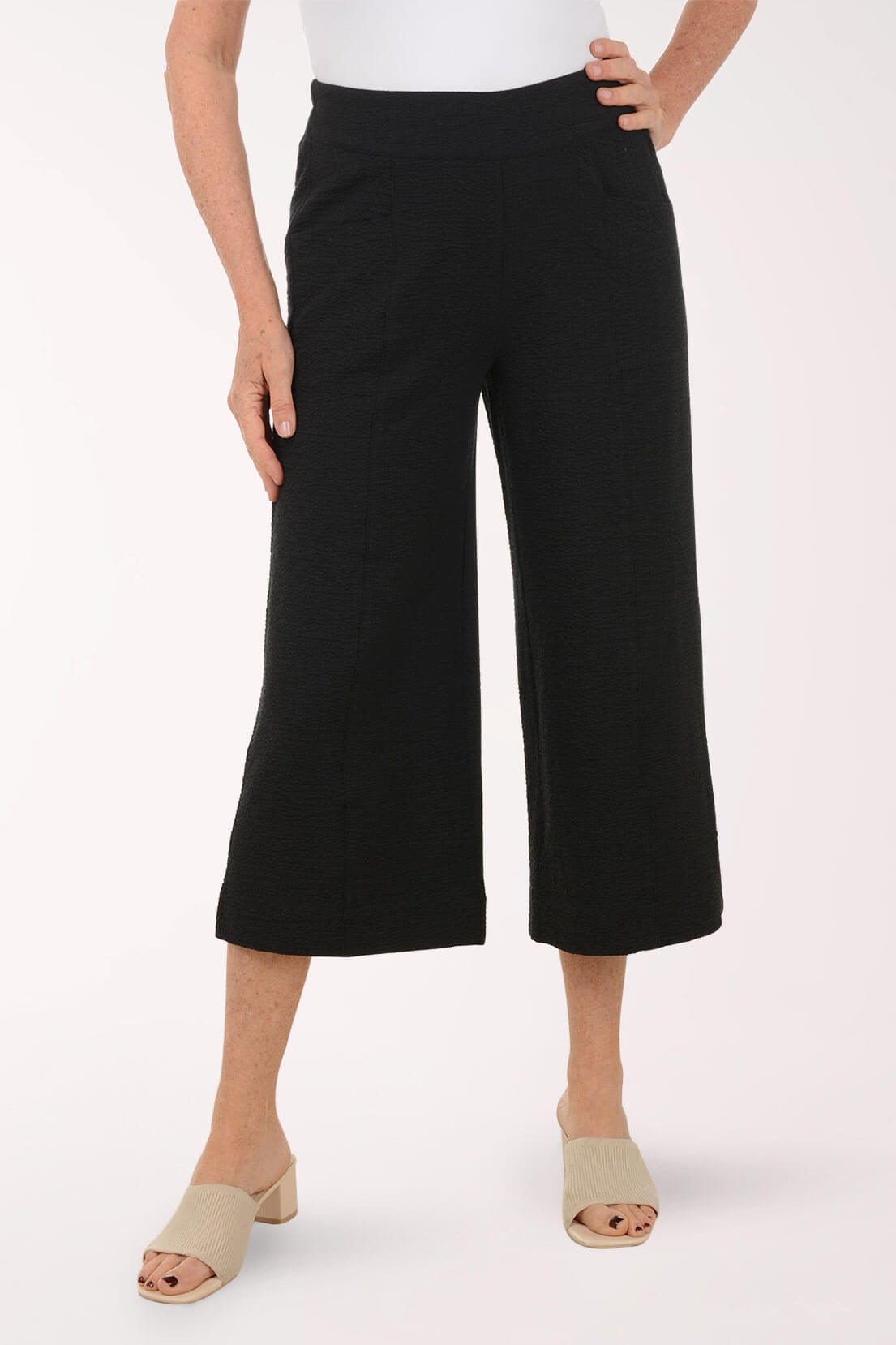 Person wearing black wide-leg pants on a white background