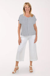 Woman wearing a black and white striped top and white pants on a white background